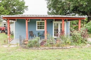 A small blue house with a porch, two chairs, and a garden in front.