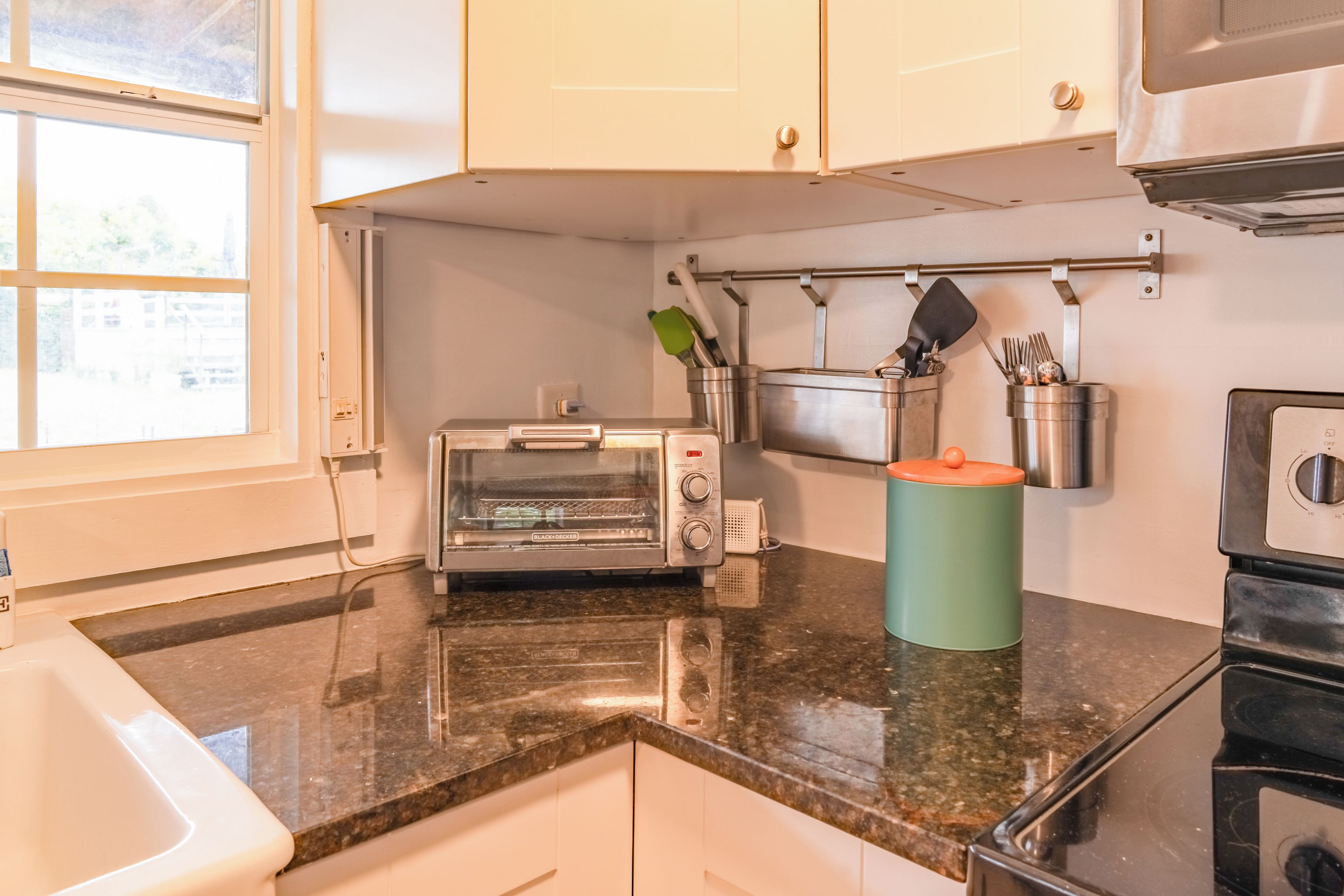 A kitchen with a built-in toaster, a kettle, and a coffee maker on the countertop.