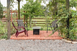 An outdoor seating area with two chairs and a table, surrounded by a wooden pergola and greenery. - Pangola Cottage (Land O' Lakes)