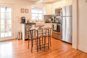 A modern kitchen with a dining area, stainless steel appliances, and a view of the outdoors.