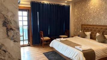 Un dormitorio moderno con una cama grande, piso de madera, techo con iluminación empotrada y vista al exterior a través de una ventana.