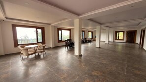 A spacious room with a dining area, large windows, and a view of the outdoors.