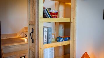 A wooden shelf unit with books, a DVD player, and board games.