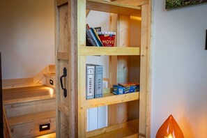 A wooden shelf unit with books, a DVD player, and board games.