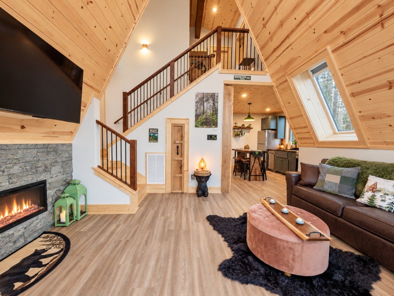 A spacious loft with a wooden interior, a fireplace, a staircase, and a dining area.