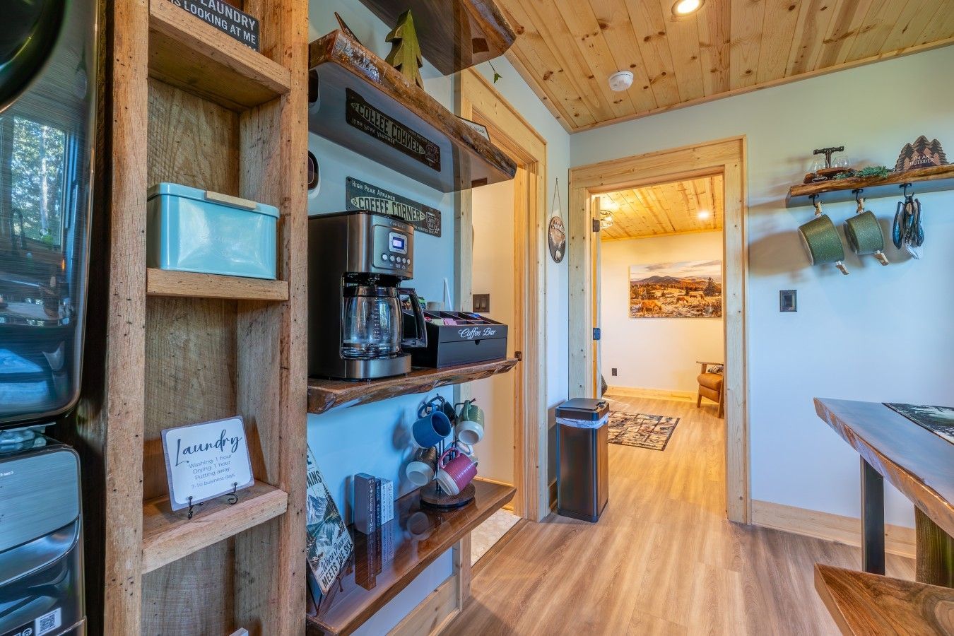 Una cucina accogliente con scaffali in legno, una macchina da caffè e un'area pranzo con tavolo e sedie.