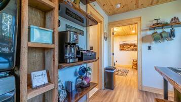 Una cucina accogliente con scaffali in legno, una macchina da caffè e un'area pranzo con tavolo e sedie.