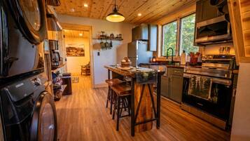 Una cucina con pavimento in legno, un'isola centrale con sgabelli, forno a incasso e un'ampia finestra.