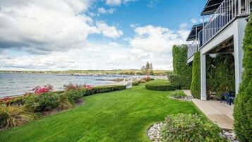 Une propriété située au bord de l’eau, dotée d’une pelouse bien entretenue, d’un espace patio et offrant une vue sur l’eau.