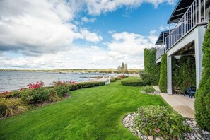 A waterfront property with a well-maintained lawn, a patio area, and a view of the water. - Beachside Escape: Waterfront view: 1 block to town (Boyne City)