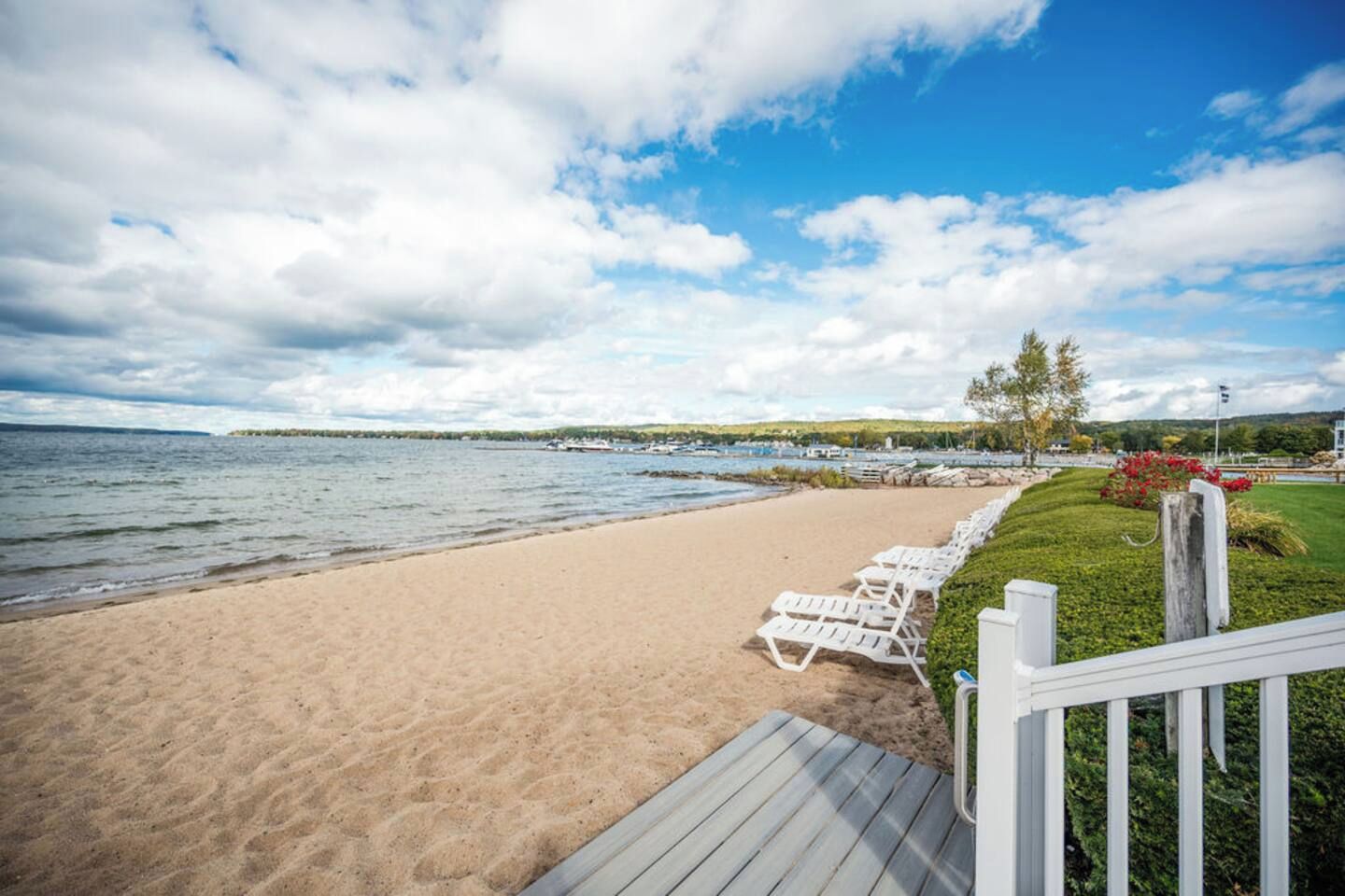 Une plage avec une terrasse en bois et des chaises longues blanches.