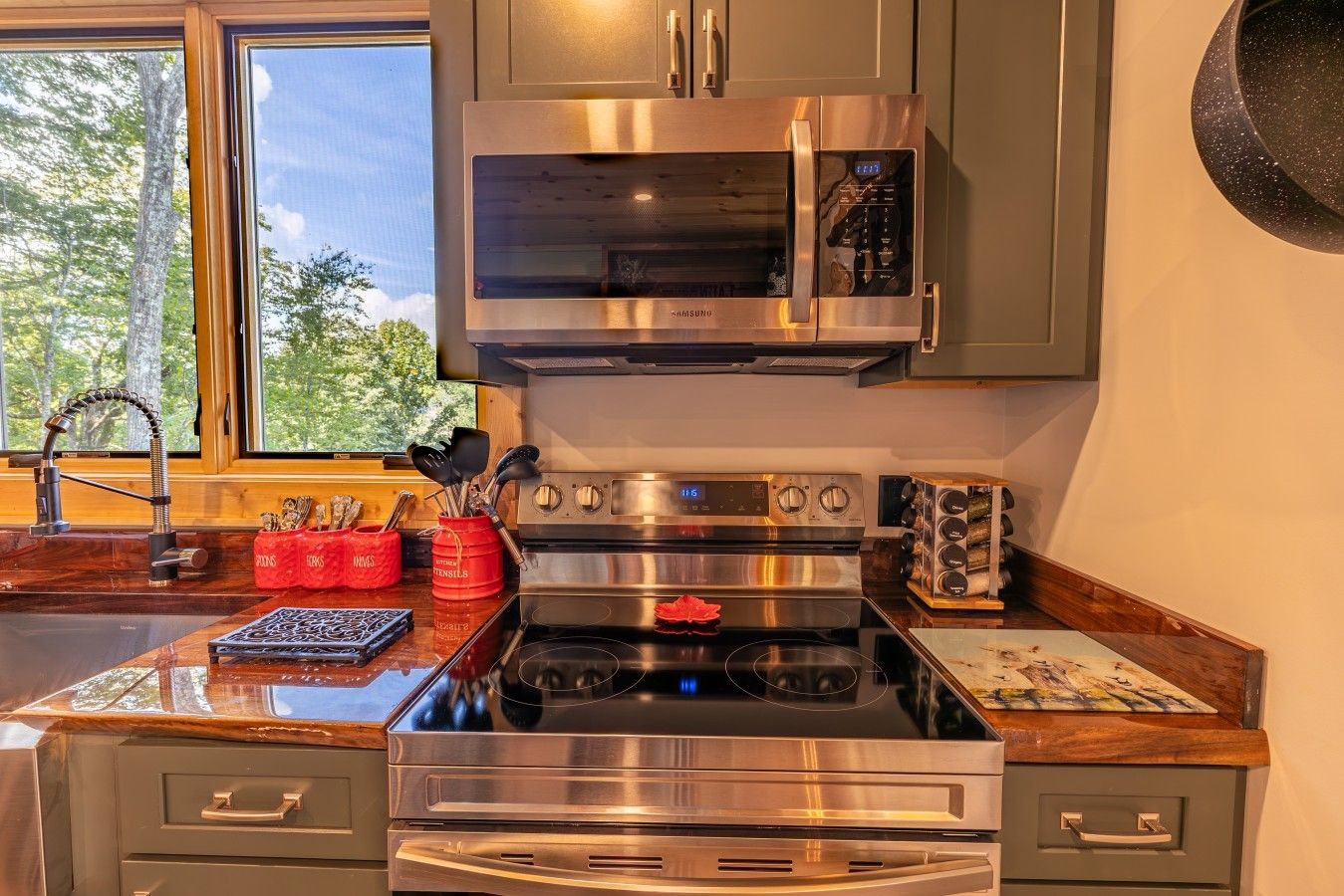 Una cocina moderna con electrodomésticos de acero inoxidable, microondas, horno y un lavabo con grifo.