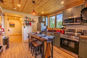 Una cucina moderna con pavimento in legno, elettrodomestici in acciaio inossidabile e un angolo bar.