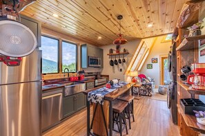Eine moderne Küche mit Edelstahlgeräten, Holzboden und einem Essbereich mit Tisch und Stühlen.