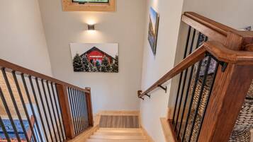 A wooden staircase with a handrail, a wall-mounted picture, and a small window at the top.