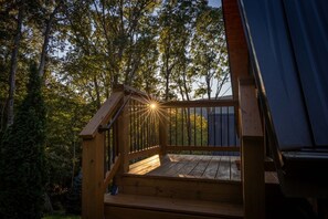 Une terrasse en bois avec une rambarde, entourée d’arbres.