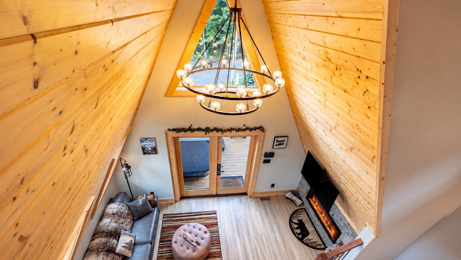 A cozy interior with a wooden ceiling, a fireplace, a sofa, and a rug.