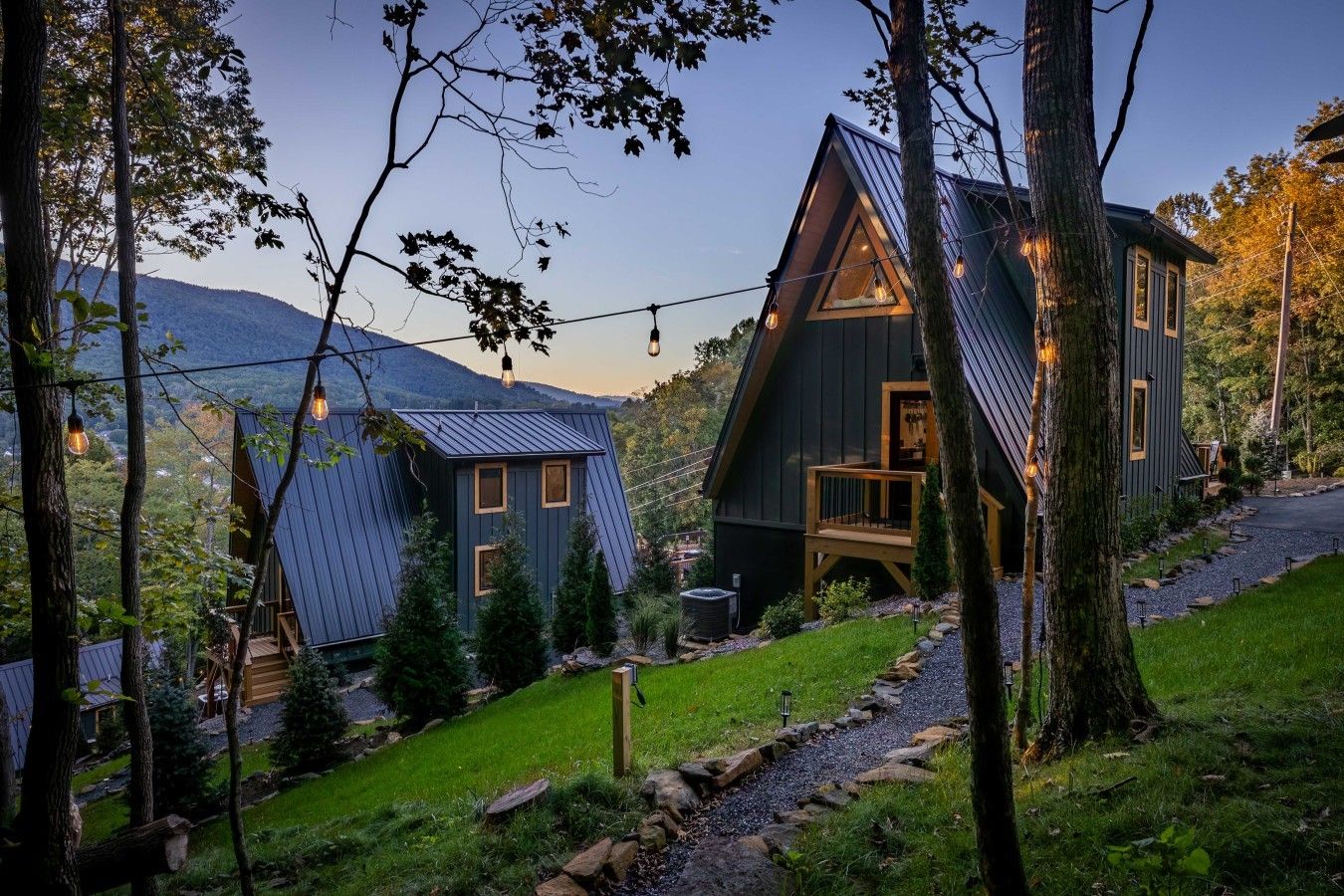 A cabin with a sloped roof, a deck, and a view of the surrounding forest and mountains.