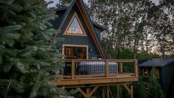A cabin with a wooden deck and a triangular roof.