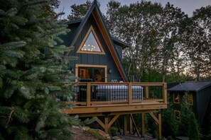 A cabin with a wooden deck and a triangular roof.