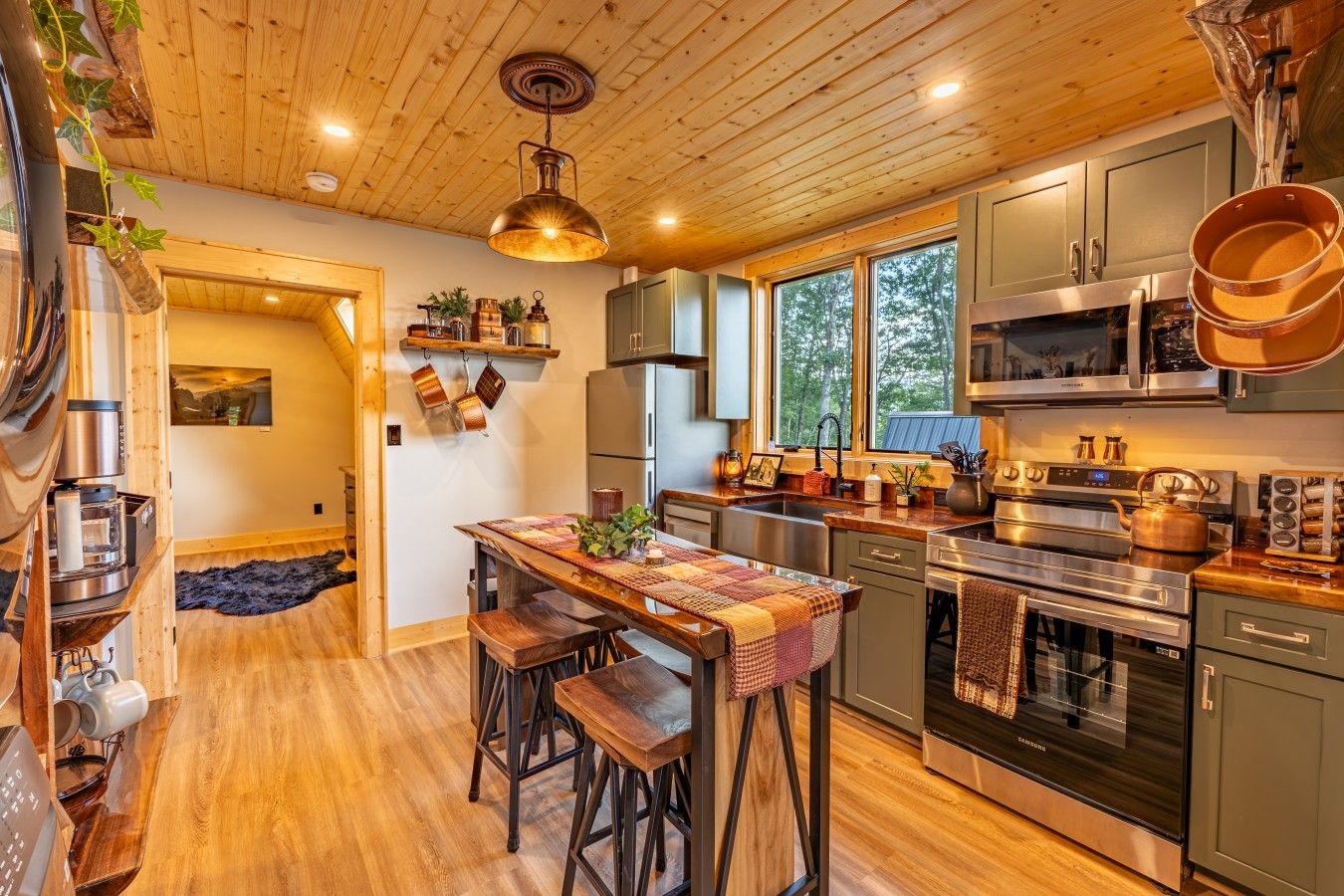 Una cocina moderna con suelo de madera, electrodomésticos de acero inoxidable y una isla central con taburetes.