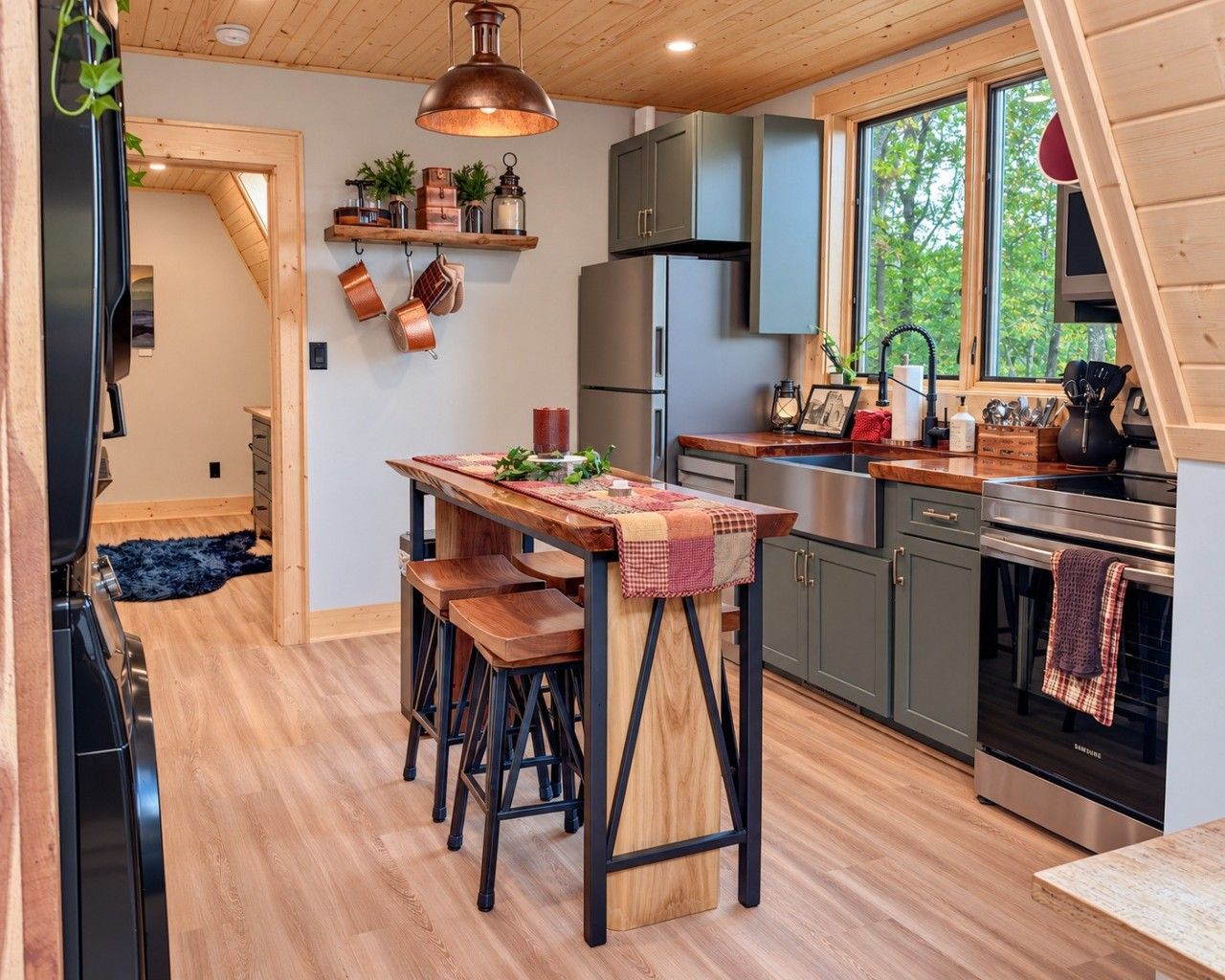 A modern kitchen with a wooden table, bar stools, and stainless steel appliances.