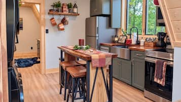 A modern kitchen with a wooden table, bar stools, and stainless steel appliances.