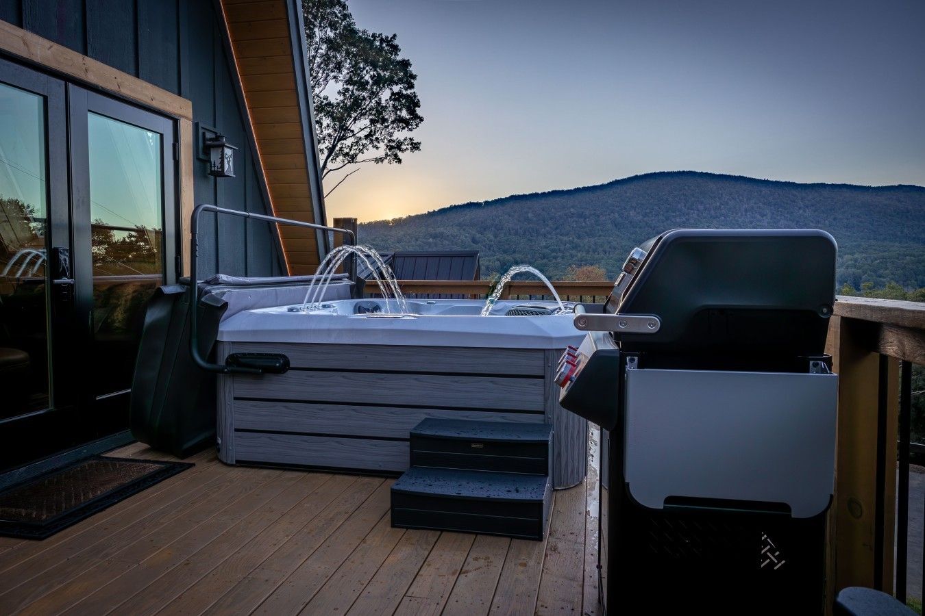 A hot tub on a wooden deck with a view of a mountain range.