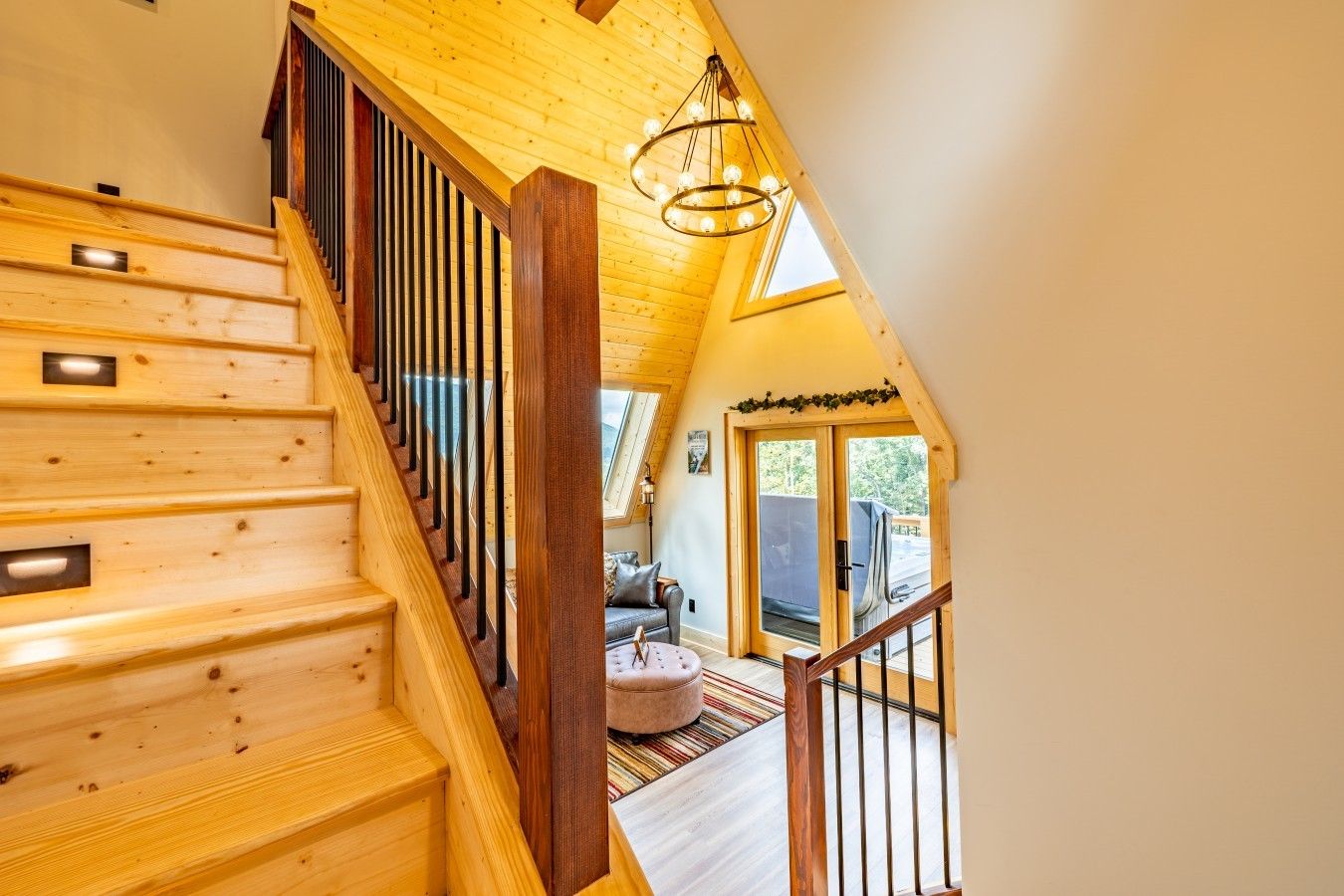 Una escalera de madera con vistas a una sala de estar y un puerta corrediza que da al exterior.