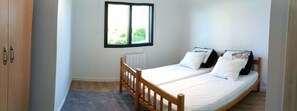 Un dormitorio con una cama individual, una ventana, un radiador y un armario de madera.