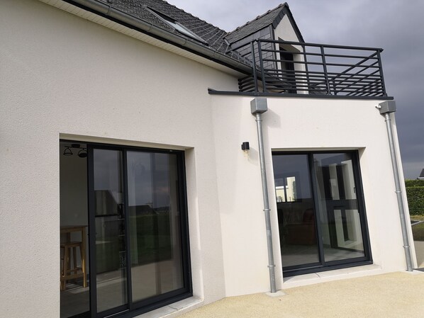A modern building with large sliding glass doors and a balcony with metal railings.