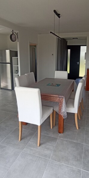 A dining area with a rectangular table, six chairs, and a patterned tablecloth. - A Stay in Le Loc'h, Plogoff, Finistère, Brittany (Plogoff)