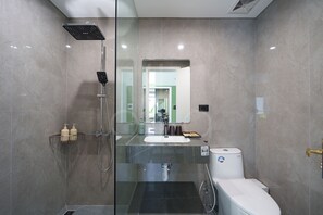 Un baño moderno con ducha envuelta en vidrio, lavamanos y retrete.