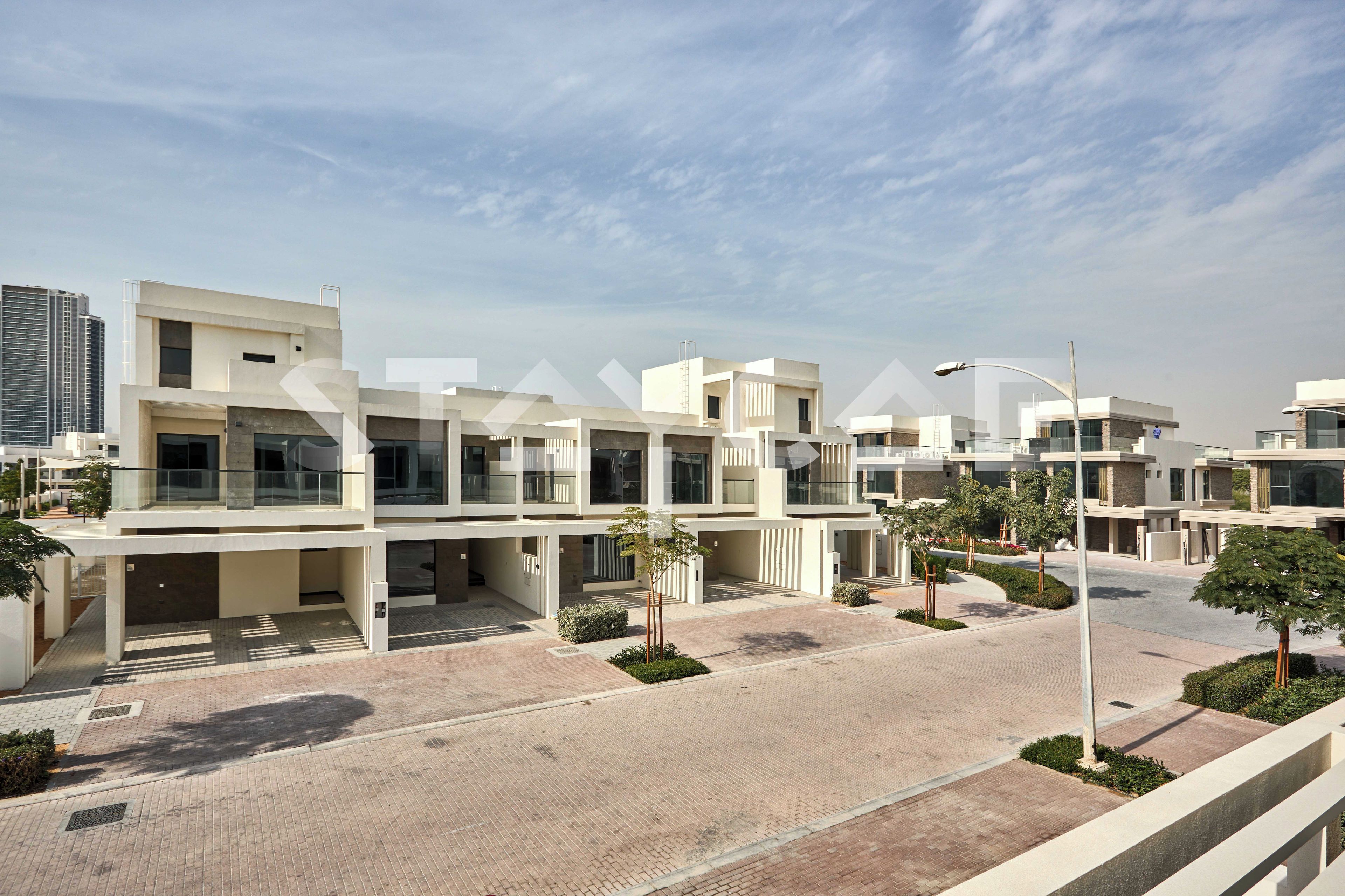 A modern residential complex with multiple buildings, paved walkways, and minimal landscaping.