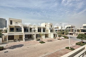A modern residential complex with multiple buildings, paved walkways, and minimal landscaping. - Staycae- 3BR Luxury Villa, Damac Hills (Dubai)