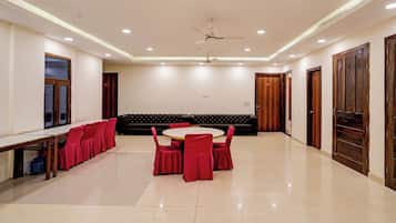 A conference room with a round table, red chairs, a black sofa, and wooden doors.