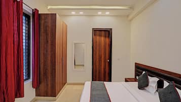 A bedroom with a bed, a wardrobe, a door, and a window with curtains.