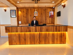 Una reception con piano in legno, una persona seduta e quadri appesi al muro.