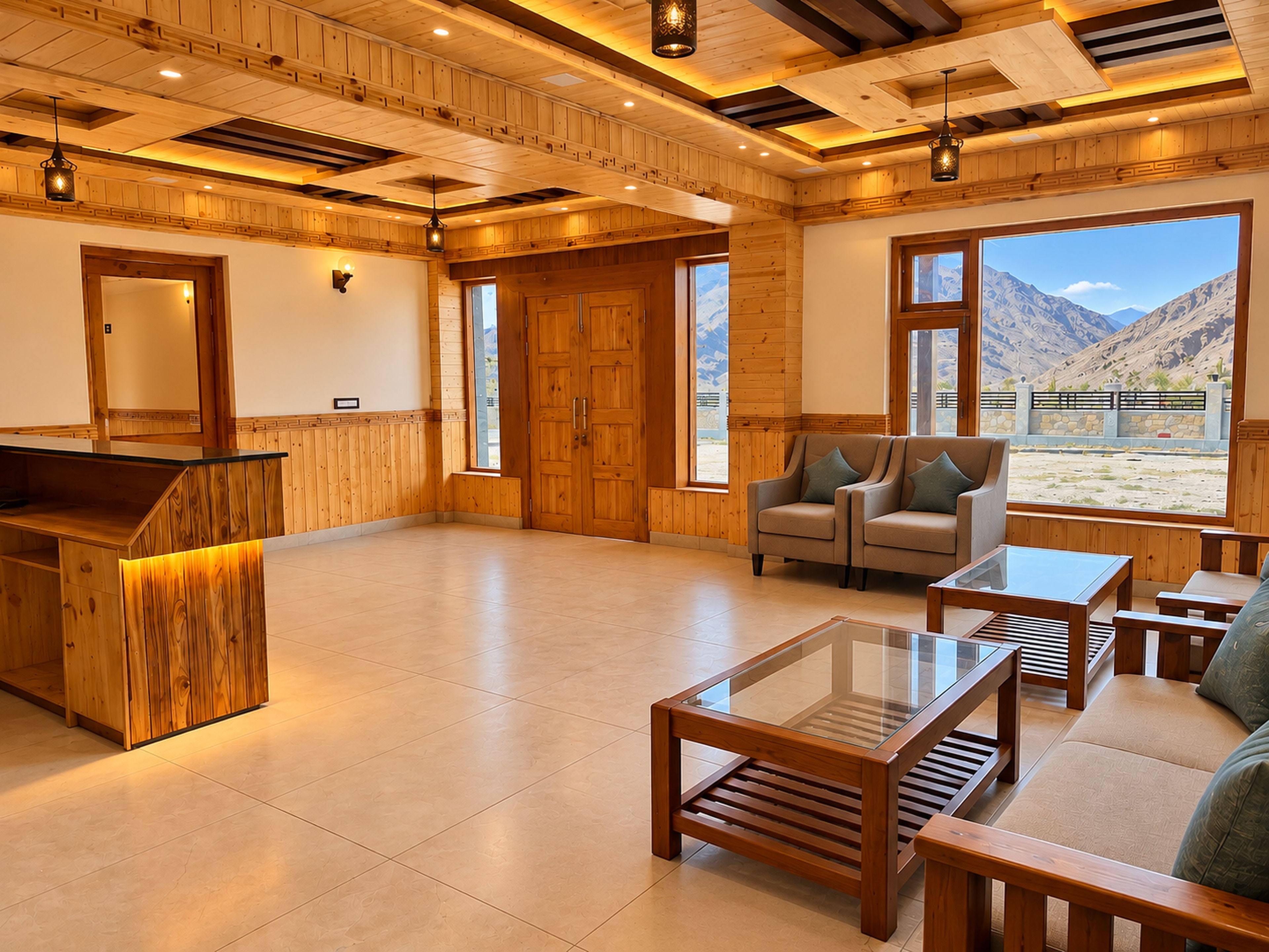 Amplia habitación con paneles de madera, una recepción, zona de estar con sofás y mesas, y grandes ventanales con vistas a las montañas.
