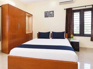 A bedroom with a bed, wardrobe, bedside table, and a window with curtains. - Hotel O Ooty Mountainview Formerly Mist (Ooty)