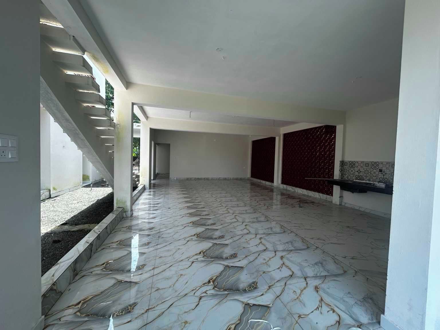 A spacious interior with a marble floor, a staircase, and a wall with a decorative pattern.