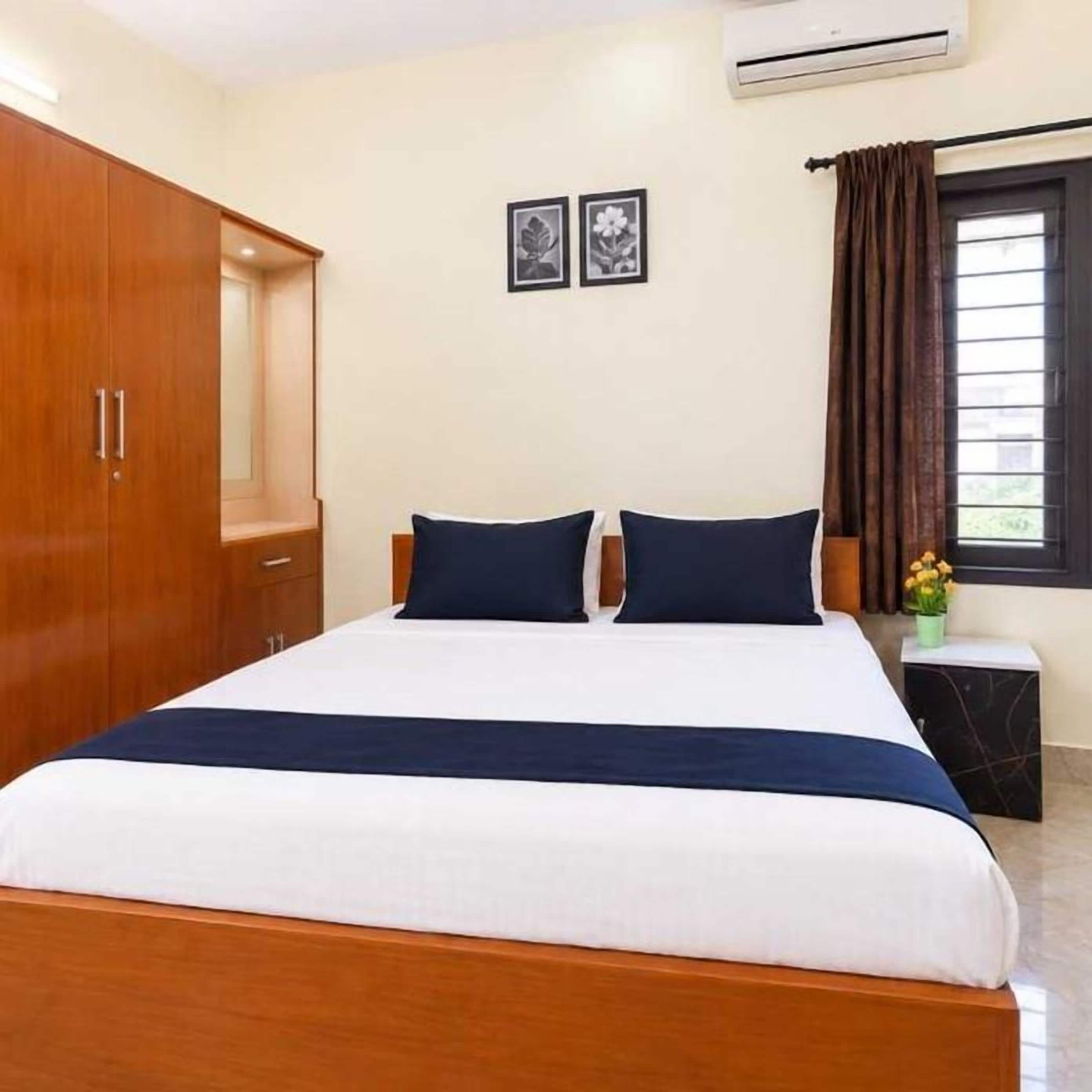 A bedroom with a bed, a wardrobe, a nightstand, and a window with curtains.