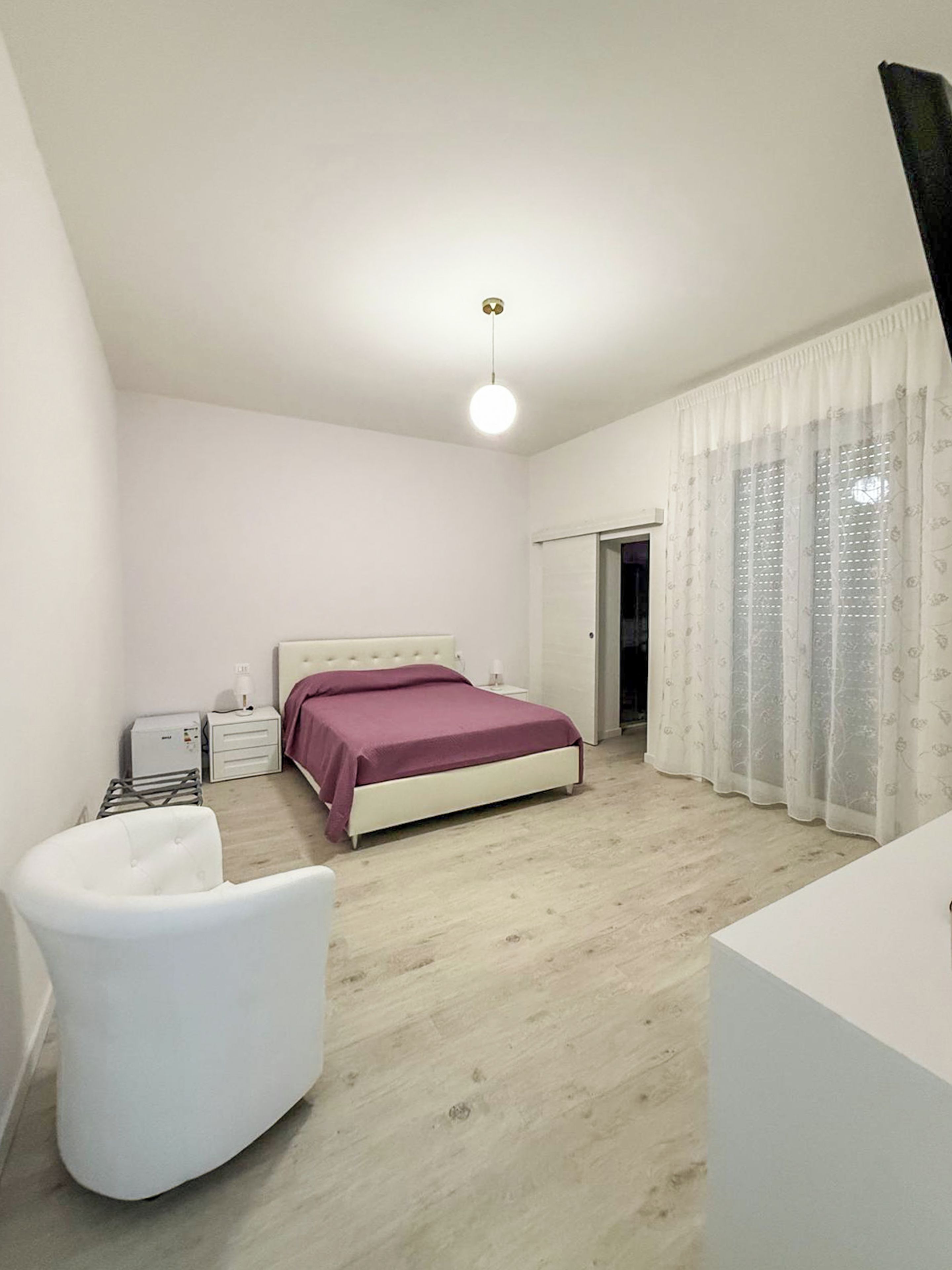 A bedroom with a bed, bedside tables, a chair, and a wardrobe.