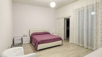 A bedroom with a bed, bedside tables, a chair, and a wardrobe.