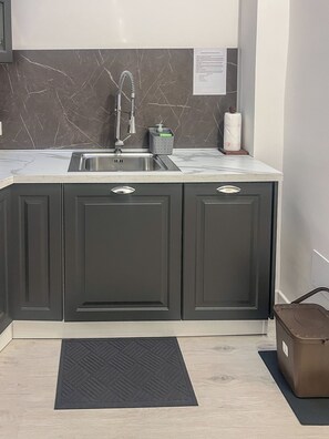 A kitchen with dark cabinets, a stainless steel sink, and a marble backsplash.