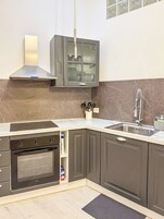 Una cocina con horno empotrado, pileta de acero inoxidable y escurreplatos.