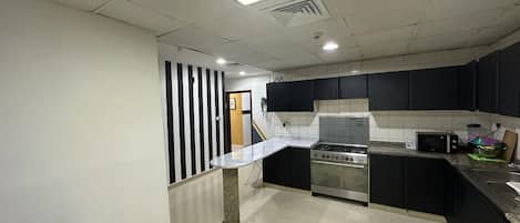 A kitchen with a stove, microwave, and a dining area with a table and chairs.
