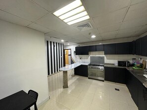 Una cocina equipada con estufa, microondas y un comedor con mesa y sillas.
