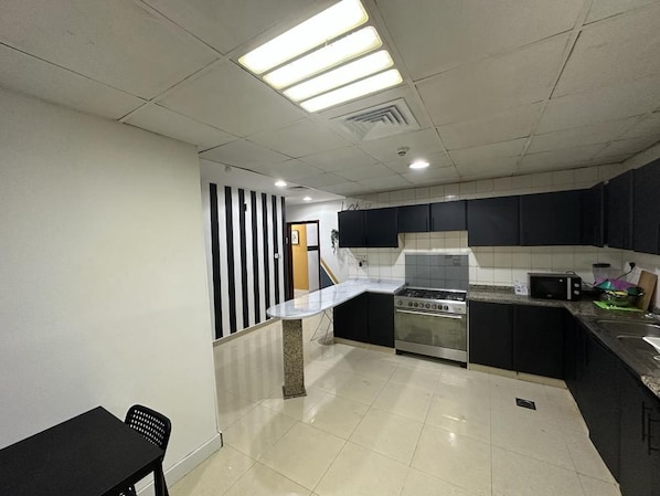 A kitchen with a stove, microwave, and a dining area with a table and chairs.