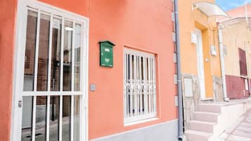 A building with a number 7 sign, a green mailbox, and a window with metal bars.